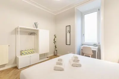 a white room with a white bed and a desk at Hostly-Suite Apartment Laterano-Walk to Colosseum in Rome