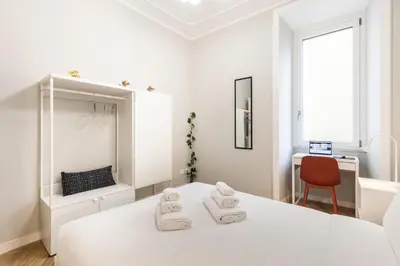 a white bedroom with a white bed and a desk at Hostly-Suite Apartment Laterano-Walk to Colosseum in Rome