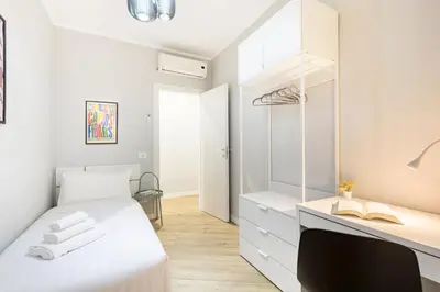 a bedroom with a white bed and a desk at Hostly-Suite Apartment Laterano-Walk to Colosseum in Rome