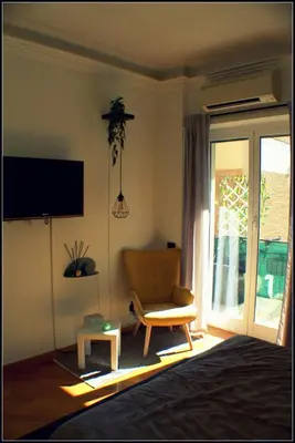a living room with a chair and a tv and a window at Il Cupolone in Pineta - Two steps in the pinewood towards the Vatican! in Rome
