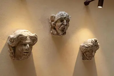 a wall with statues of heads on a wall at Sinopia Home Gallery - WelcomeToRhome in Rome