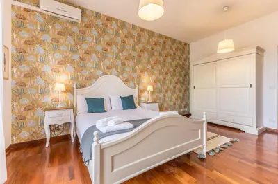 a bedroom with a white bed with a floral wallpaper at Casa Nina Ostiense - Roma Tre - by GHOR in Rome