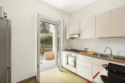 a kitchen with white cabinets and a door leading to a patio at San Paolo Private Garden Home in Rome