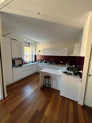 a kitchen with white cabinets and a wooden floor at Bright Apartment in San Lorenzo - Feel at Home in Rome