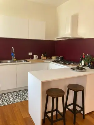a kitchen with a white counter and two stools at Bright Apartment in San Lorenzo - Feel at Home in Rome