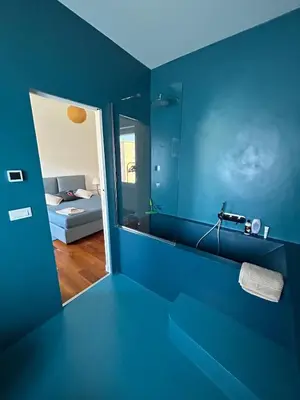 a blue bathroom with a mirror and a bed at Bright Apartment in San Lorenzo - Feel at Home in Rome