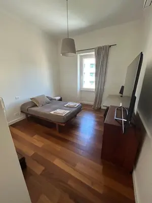 a bedroom with a bed and a wooden floor at Bright Apartment in San Lorenzo - Feel at Home in Rome