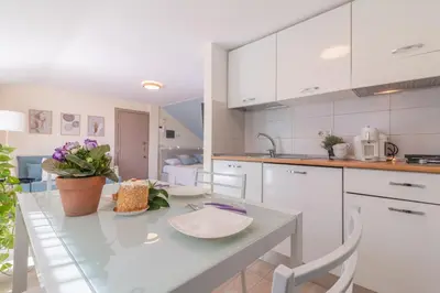a kitchen with white cabinets and a table and chairs at Luxury Maison Dei Colli in Rome