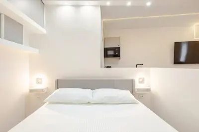 a white bedroom with a white bed and a television at Tito Livio Vatican Home in Rome
