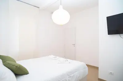 a white bedroom with a bed and a tv at Modern two-room apartment for 2, 20 minutes from Termini in Rome
