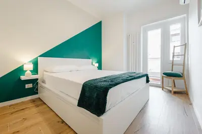 a bedroom with a white bed with a green accent wall at Smeraldo Vatican Moments in Rome