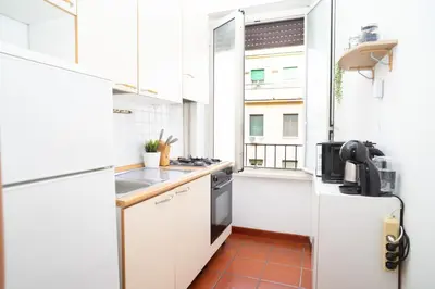 a small kitchen with white cabinets and a window at Modern and Central One-Bedroom, 10 min from Colosseum in Rome