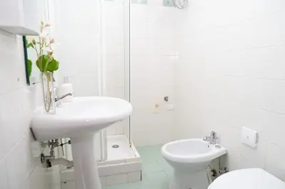 a white bathroom with a sink and a toilet at Modern and Central One-Bedroom, 10 min from Colosseum in Rome