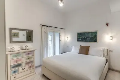 a white bedroom with a large bed and a dresser at Dante Secret Home in Rome