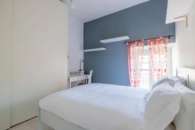 a bedroom with a white bed and a blue wall at Dante Secret Home in Rome
