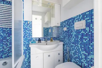 a blue tiled bathroom with a sink and a toilet at Dante Secret Home in Rome