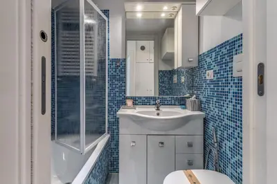 a blue tiled bathroom with a sink and a toilet at Dante Secret Home in Rome