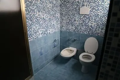 a blue tiled bathroom with a toilet and a bidet at Super attico Eur in Rome