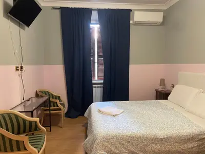 a bedroom with a bed and a desk and a window at Ines Guest House in Rome