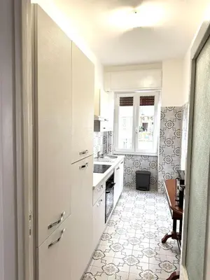 a kitchen with white cabinets and a table at Piramide-Ostiense Two Bedroom Apartment in Rome
