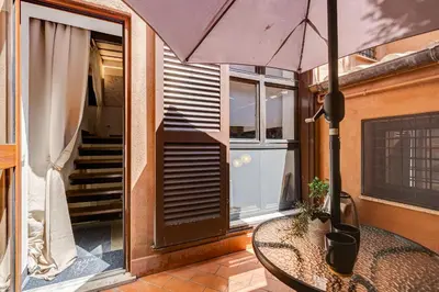 a table with an umbrella on a balcony at Trastevere Piazza Trilussa Royal Orchid apartment in Rome
