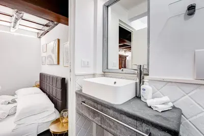 a white bathroom with a sink and a mirror at Trastevere Piazza Trilussa Royal Orchid apartment in Rome
