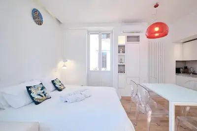 a white bedroom with a large bed and a kitchen at Elegant Apartment near the Centre - Wi-Fi & Netflix Free in Rome