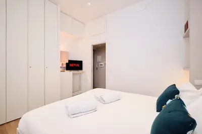 a white bedroom with a white bed and a tv at Elegant Apartment near the Centre - Wi-Fi & Netflix Free in Rome