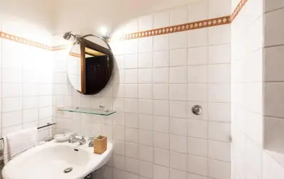 a white tiled bathroom with a sink and a mirror at Secret place in the heart of ancient Trastevere in Rome