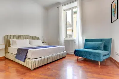 a bedroom with a bed and a blue chair at Colosseo Green Park - Home and More in Rome