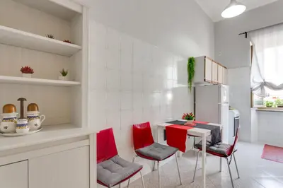 a kitchen with red chairs and a table and a refrigerator at Alice House al Vaticano in Rome