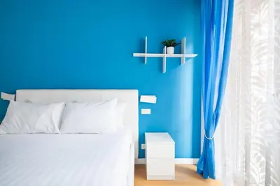 a blue bedroom with a white bed and a blue wall at Appartamento Elegante e Luminoso con Metro Vicina in Rome