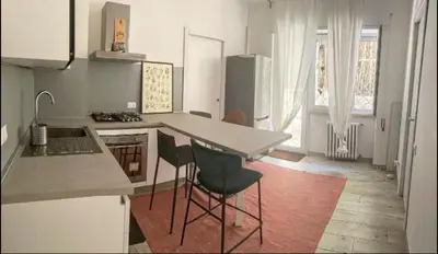 a kitchen with a counter and some chairs in it at Loft with little backyard and patio in Rome