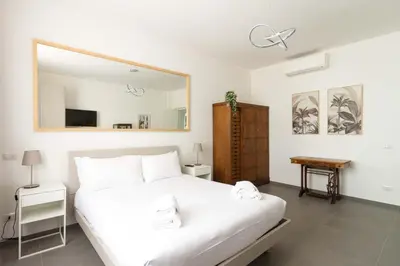 a bedroom with a white bed and a large mirror at Gilda's Home in Rome