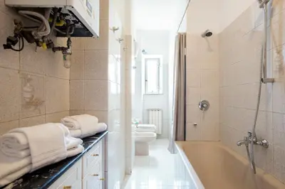 a white bathroom with a tub and a toilet at Paramount Penthouse in Rome