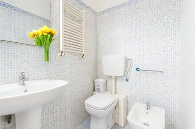 a white bathroom with a toilet and a sink at Elegantis San Giovanni Suite - Chic Apartment with Bathtub Near Historic Center, Metro & Tram Nearby in Rome