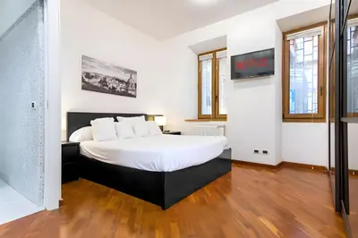 a bedroom with a large bed with white sheets at Elegantis San Giovanni Suite - Chic Apartment with Bathtub Near Historic Center, Metro & Tram Nearby in Rome
