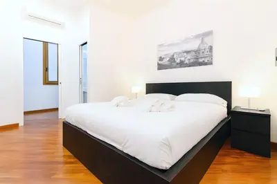 a white bedroom with a large bed with white sheets at Elegantis San Giovanni Suite - Chic Apartment with Bathtub Near Historic Center, Metro & Tram Nearby in Rome