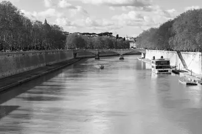 a black and white photo of a river with a bridge at Puro Suite Frezza in Rome