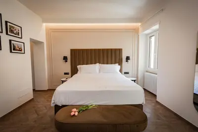 a bedroom with a large white bed with flowers on a ottoman at Puro Suite Frezza in Rome