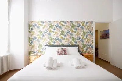 a bedroom with a white bed with a tropical wallpaper at HC - Piazza Vittorio Emanuele Dream in Rome