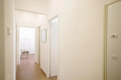 a hallway with white walls and a door and a chair at HC - Piazza Vittorio Emanuele Dream in Rome