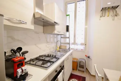 a white kitchen with a stove top oven next to a window at HC - Piazza Vittorio Emanuele Dream in Rome