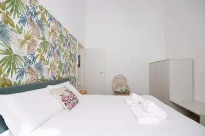 a bedroom with a white bed with a floral wallpaper at HC - Piazza Vittorio Emanuele Dream in Rome
