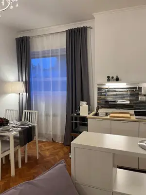 a white kitchen with a table and a dining room at Cozy Donatello Apartment in Rome