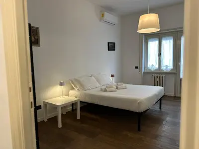 a white bedroom with a bed and a table at Le Crete Apartment in Rome