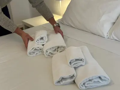 a person is making towels on a bed at Le Crete Apartment in Rome