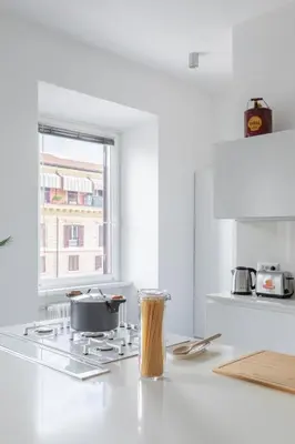 a white kitchen with a stove and a window at Trastevere Modern 4BR 4baths, WIFI, AC, custom kitchen, living room in Rome