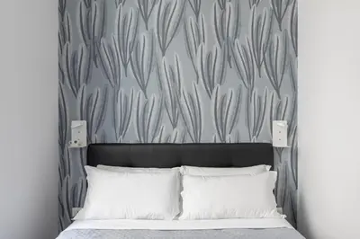 a bedroom with a bed with a headboard and a wall at Trastevere Modern 4BR 4baths, WIFI, AC, custom kitchen, living room in Rome