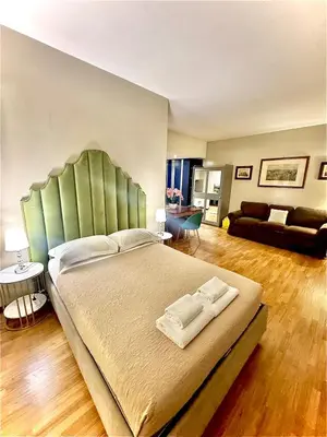 a bedroom with a large bed with a green headboard at Borghese Luxury Loft - LIBERTY COLLECTION in Rome